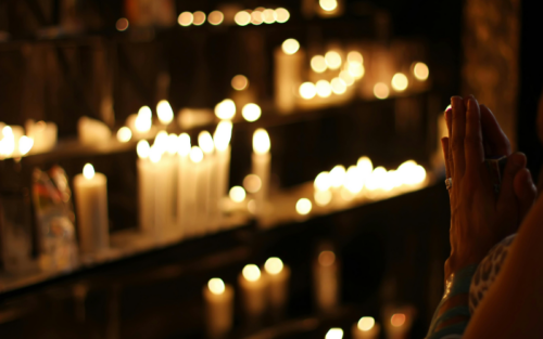 Religious beliefs, a woman praying over candles