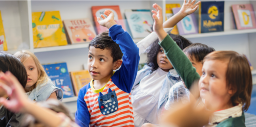 Young children put their hands up to ask a question